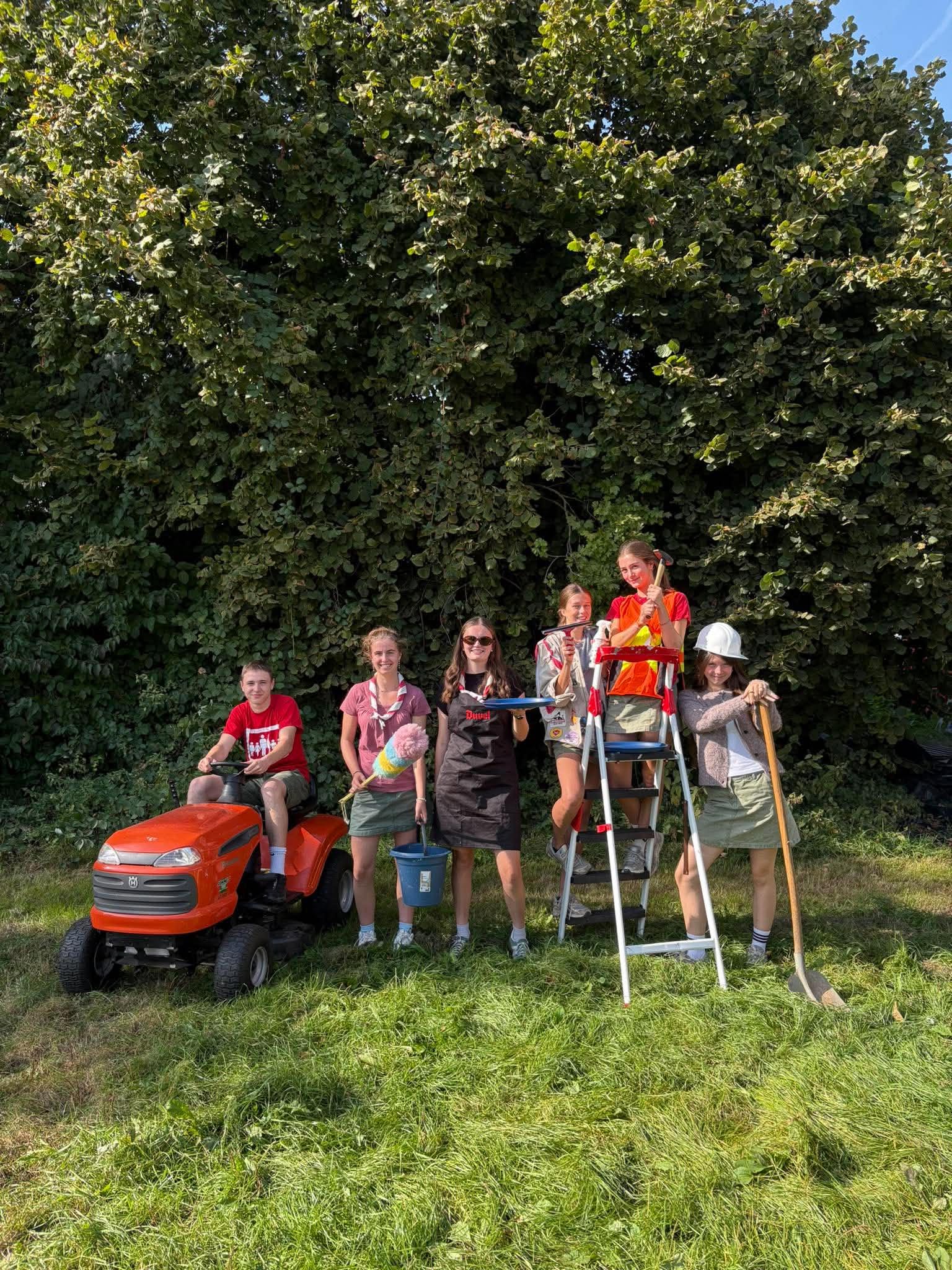 De Jins van Scouts Juventa Merchtem met grasmaaier, ladder, emmer en schop, klaar om te helpen